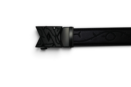 VASANA automatic belt buckle in matte black with an engraved V monogram and vine detailing on a black leather strap